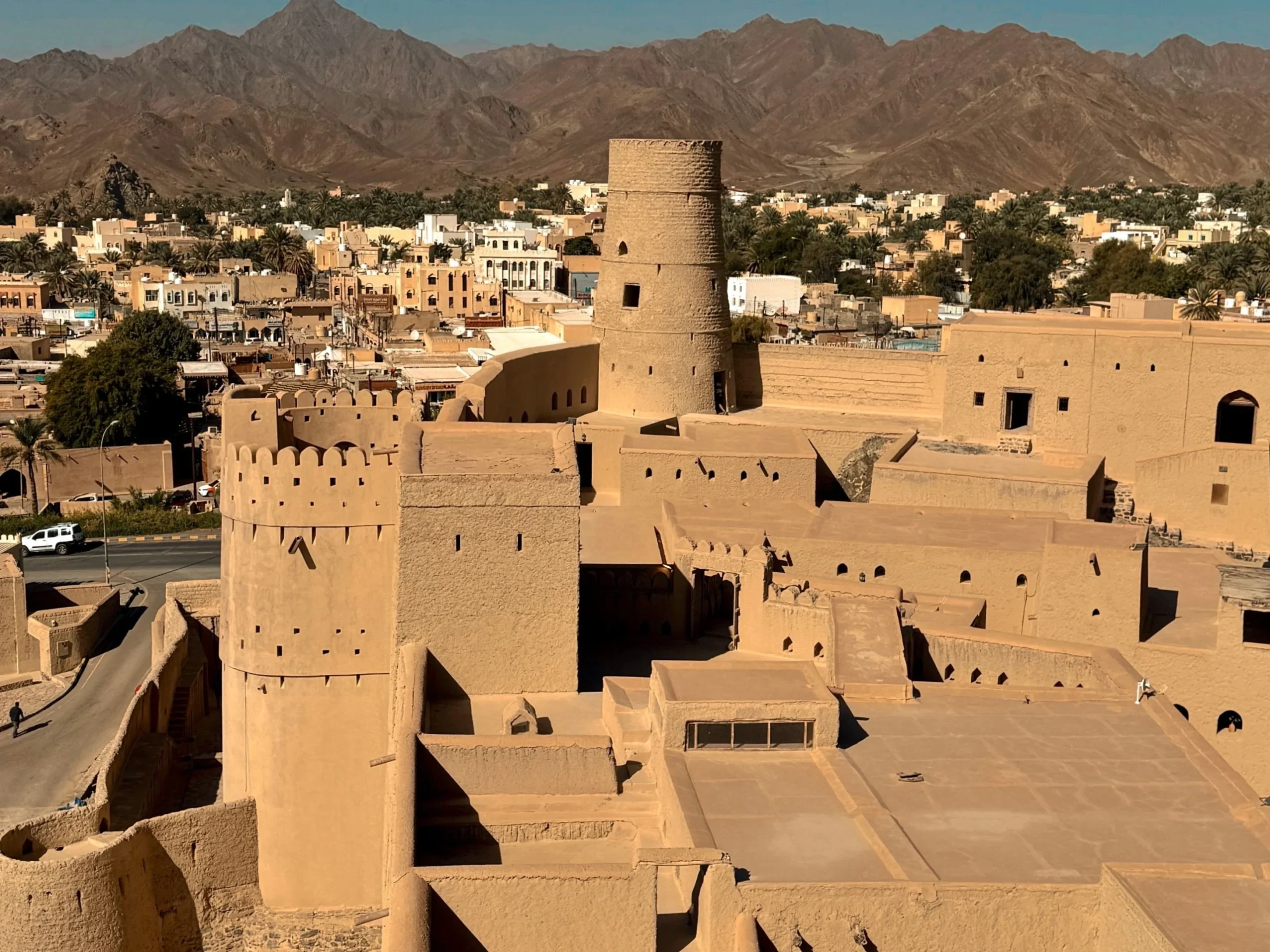 pexels-girlvsglobe86-300284270-35581420 Veduta di edifici bianchi con montagne sullo sfondo in Oman.