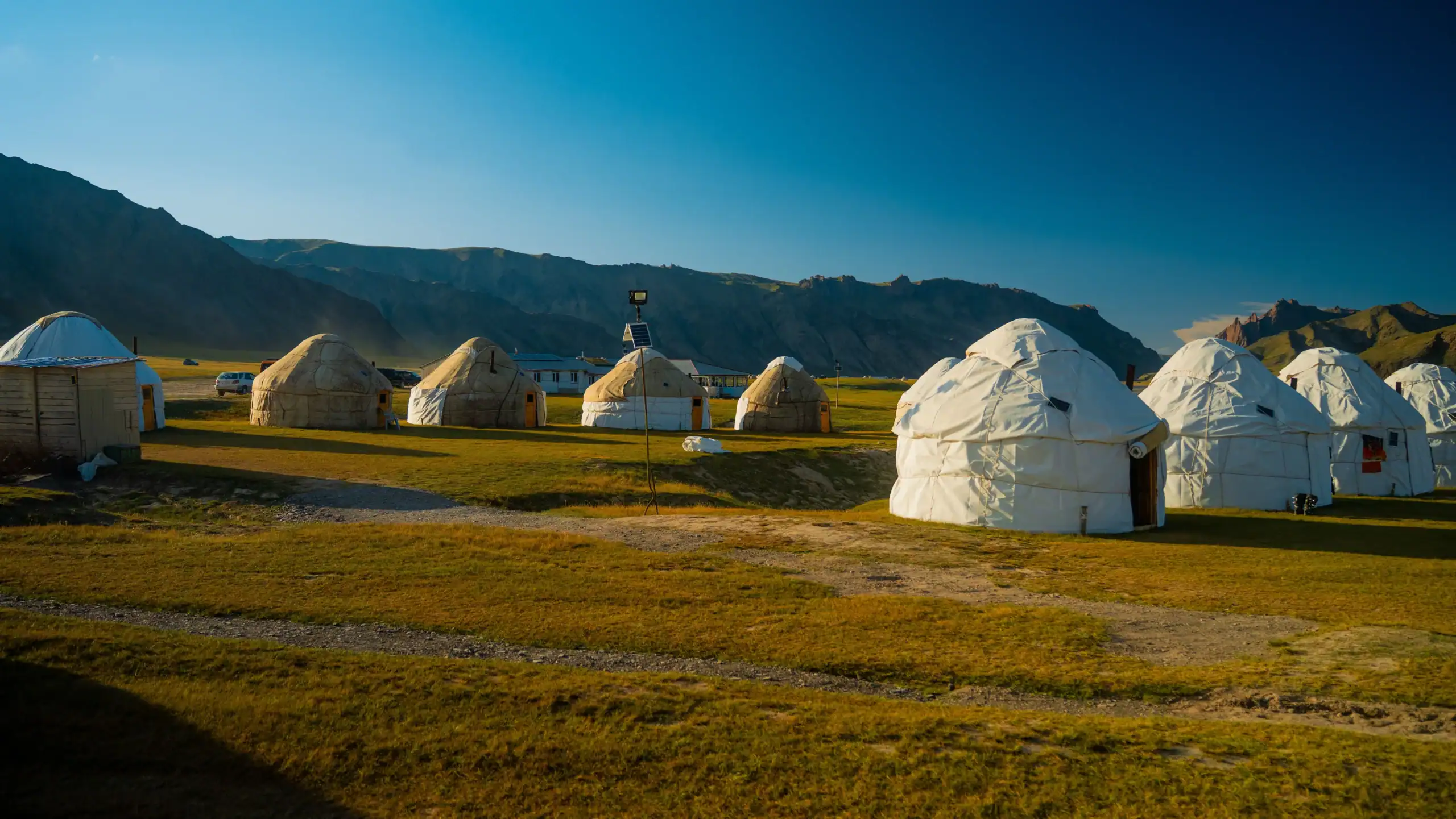 Tenda tradizionale in paesaggio con montagne innevate sullo sfondo.